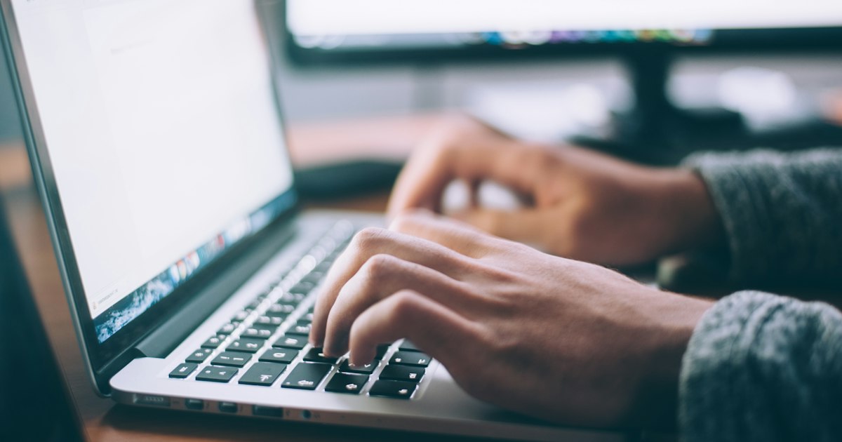 Hands typing on a laptop while managing a LinkedIn profile