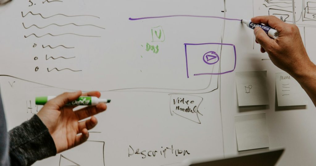 Two colleagues discussing strategy at a whiteboard