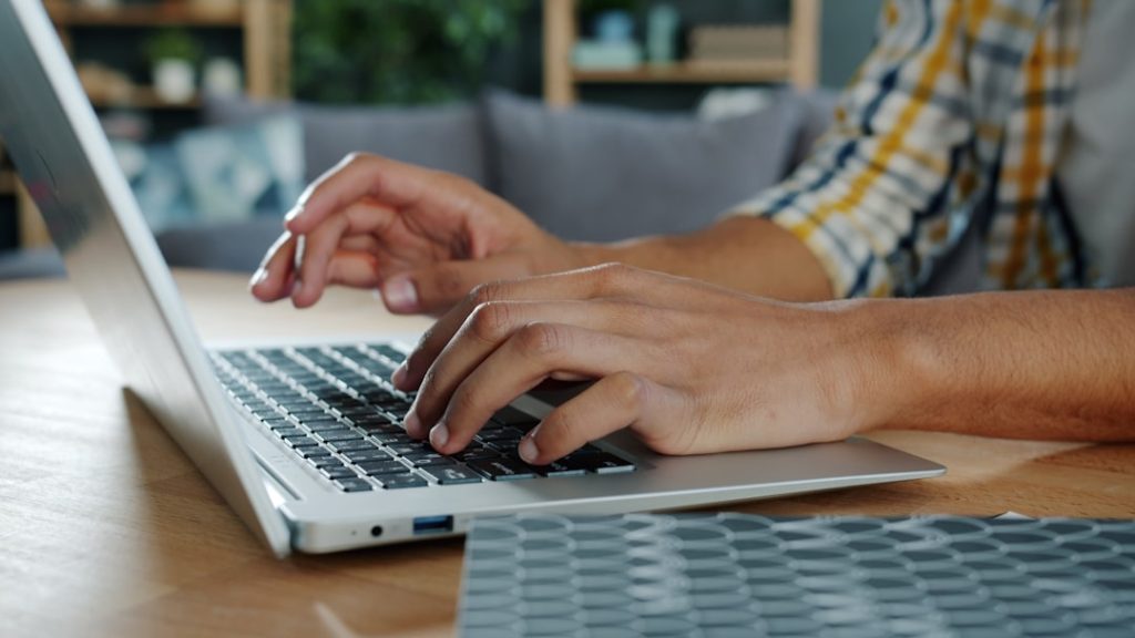 Hands typing on a laptop at a desk