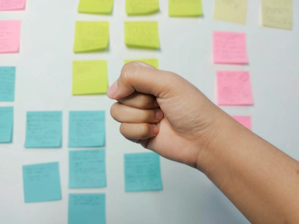 Hand holding yellow and pink sticky notes side by side for comparison