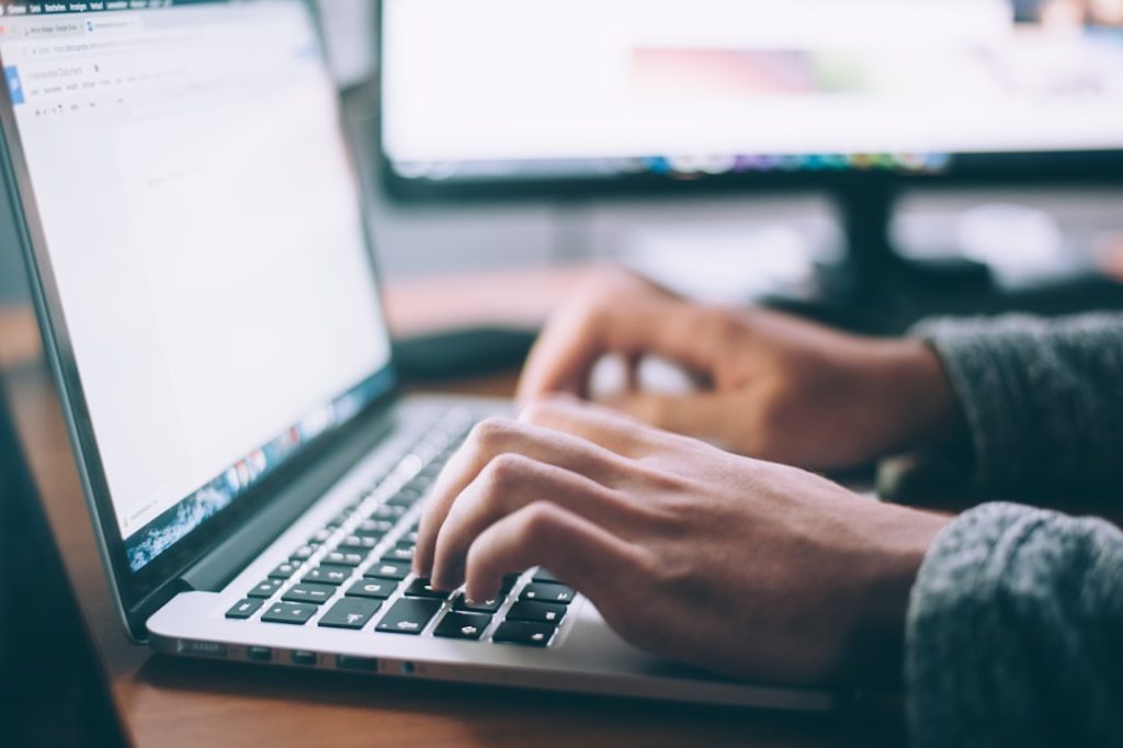 Hands typing on a laptop while editing a LinkedIn profile