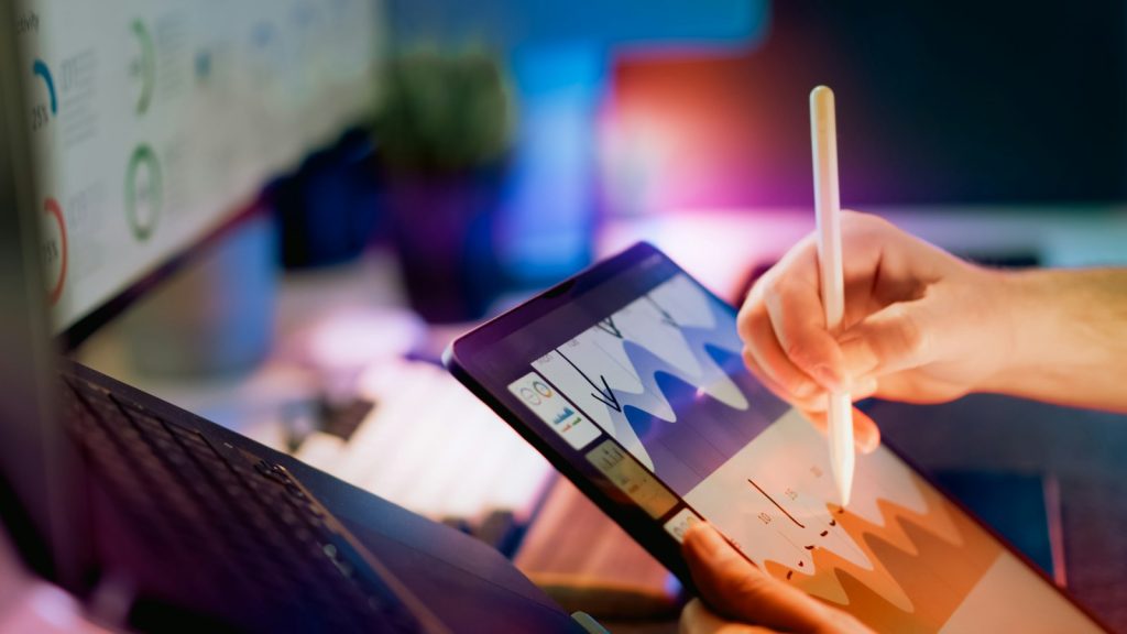 Hand using a stylus on a tablet to review a colourful analytics chart, representing a LinkedIn Social Selling Index score breakdown