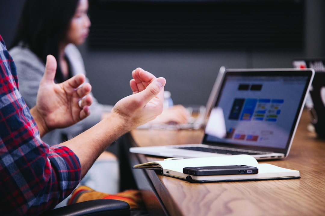 Salesperson gesturing while discussing objections during a meeting with a laptop open
