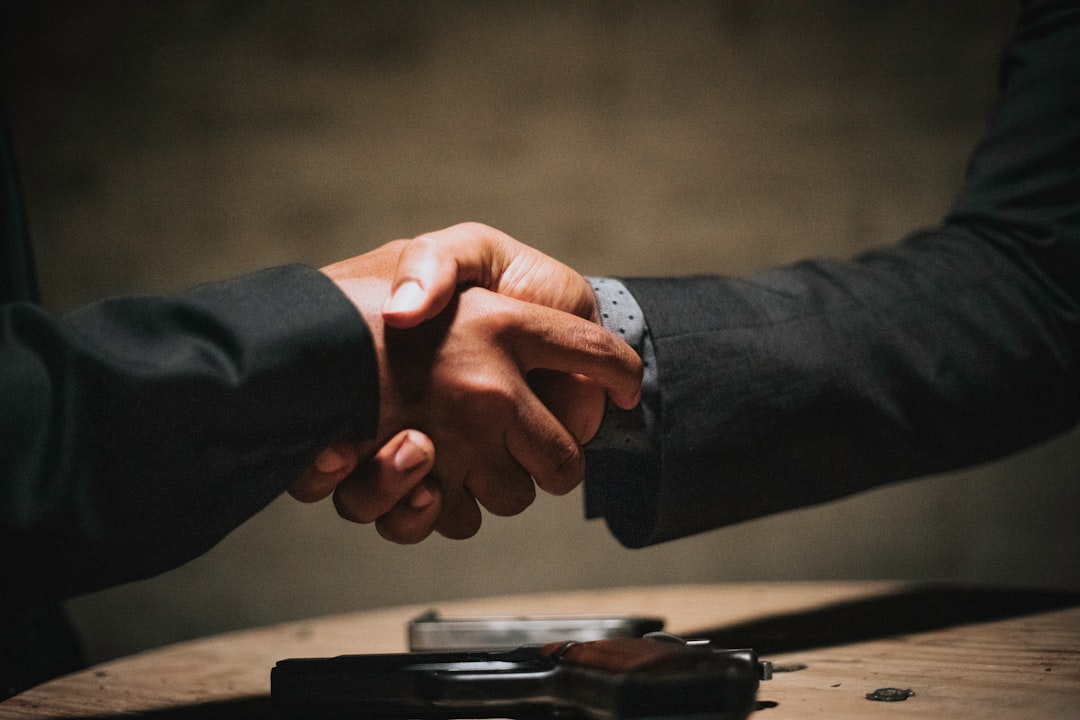 Two business people shaking hands over a wooden table after a referral introduction