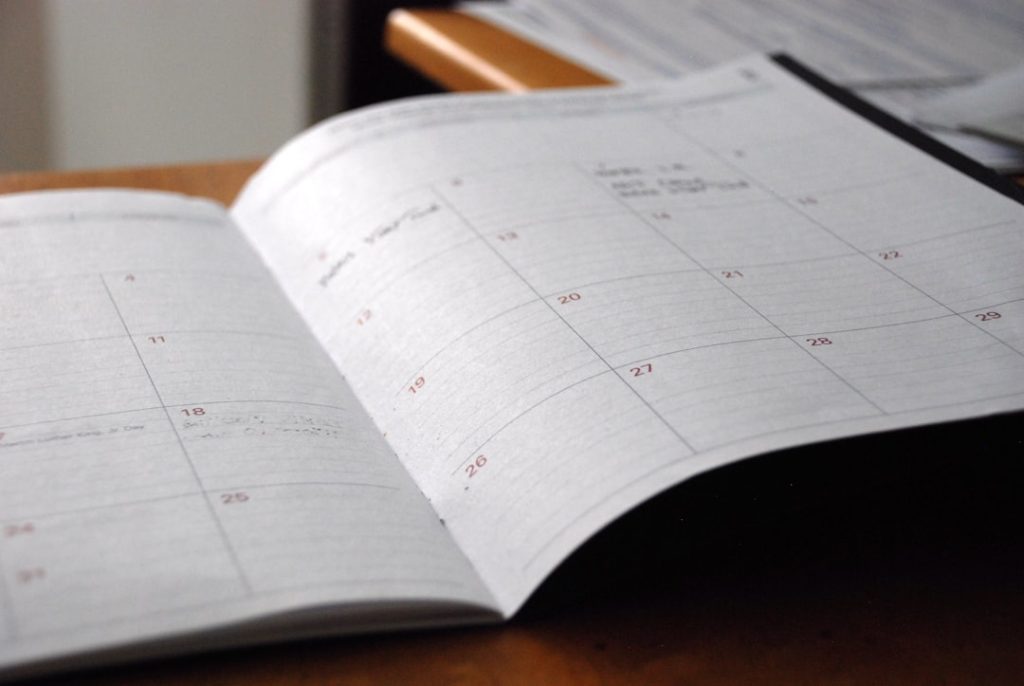 Open planner on a wooden desk used for scheduling a sales outreach cadence