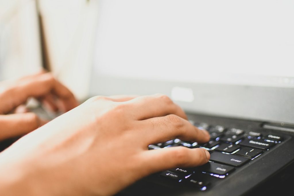 Closeup of a woman's hands typing on a laptop keyboard