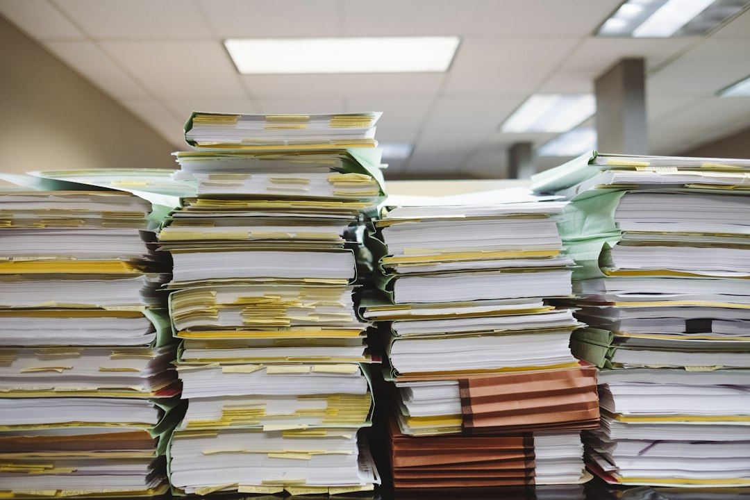 Stacks of paper documents and file folders sorted into priority piles on a desk