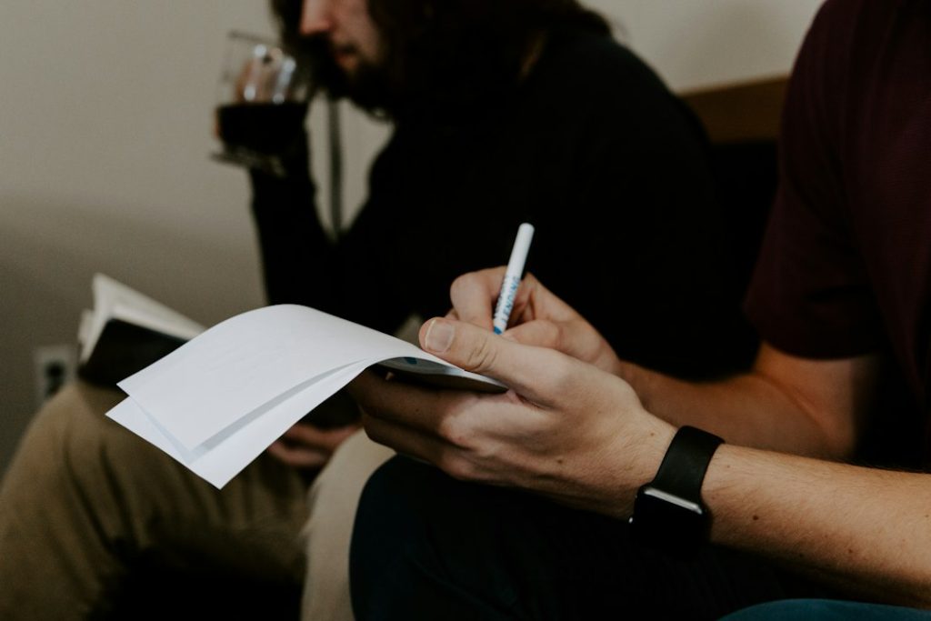 Two colleagues reviewing notes together at a desk during a meeting handoff