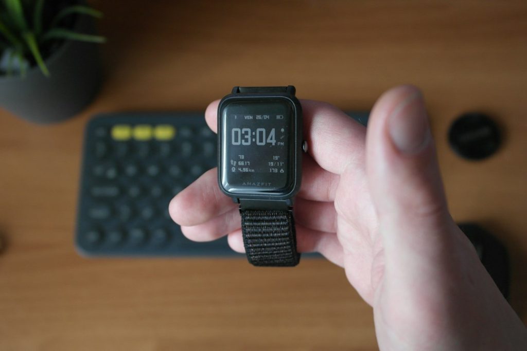 Close-up of a black smart watch showing the time on a person’s wrist at a desk
